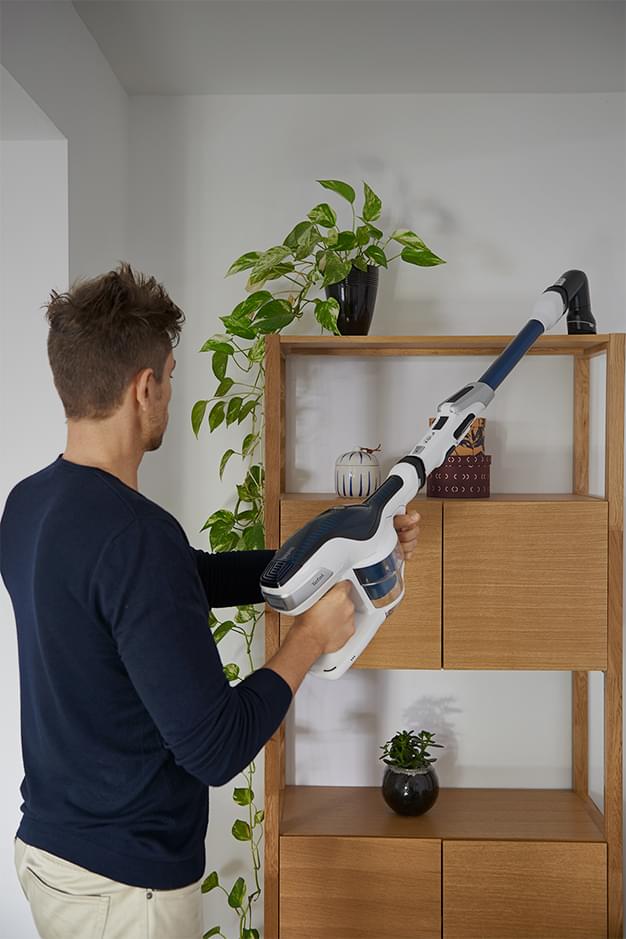 Man vacuuming above a piece of furniture